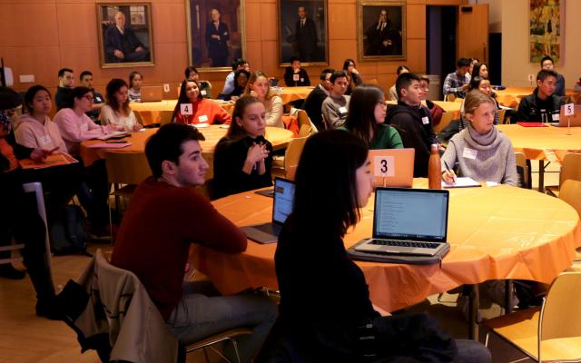 About two dozen students seated around numbered tables at a speed networking event