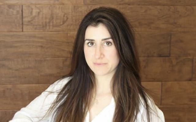 Woman with long brown hair in front of wooden panel background
