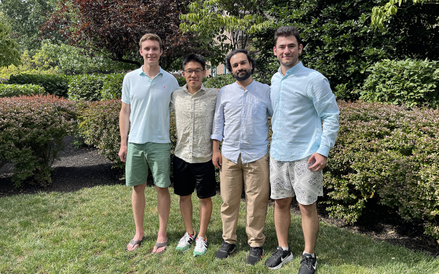Group of four students standing together outside smiling