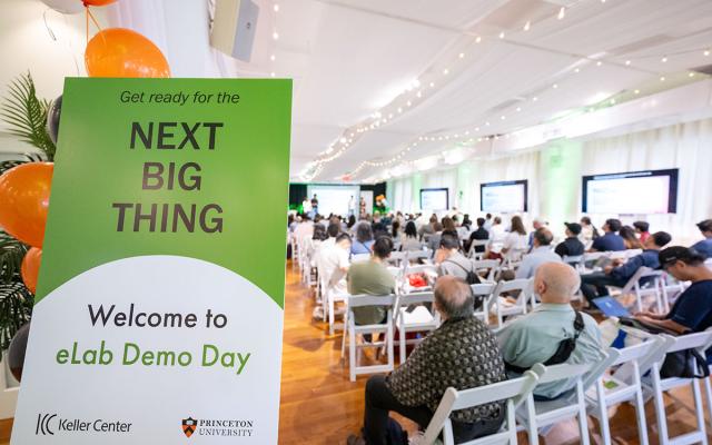 bright room full of people a sign says, "Get ready for the Next Big Thing - welcome to eLab Demo Day" with the Keller Center and Princeton University logos