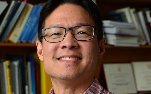 Man with glasses standing in front of bookshelf