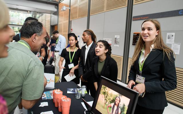 students standing at a table talking to event attendees