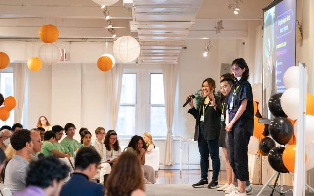 Four students on a stage presenting in front of an audience at the 2022 eLab Demo Day in New York City