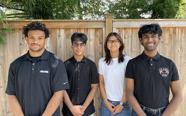 Eval team members smiling in front of wooden fence and trees