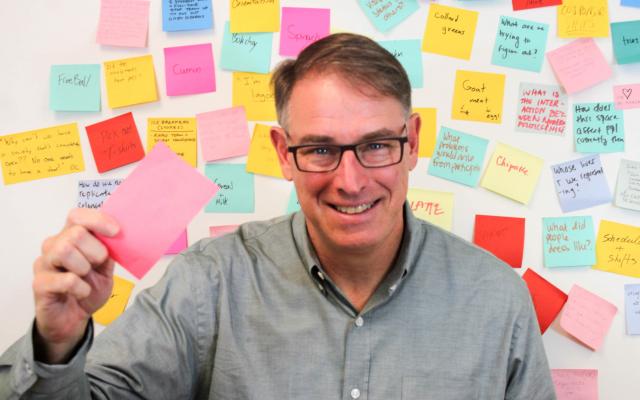 Man with glasses in front of wall of colorful post-its