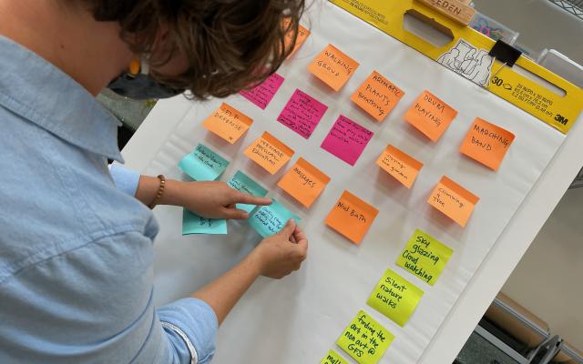 Woman standing in front of a board full of colorful sticky notes.