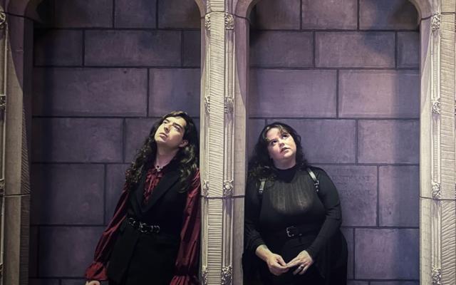 Team members stand in darkly lit individual chapel alcoves wearing gothic attire
