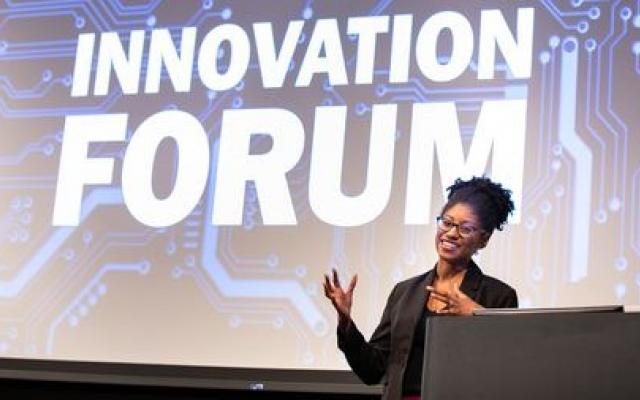 NJ Secretary of Higher Education Education Zakiya Smith Ellis at podium in front of projection of Innovation Forum logo