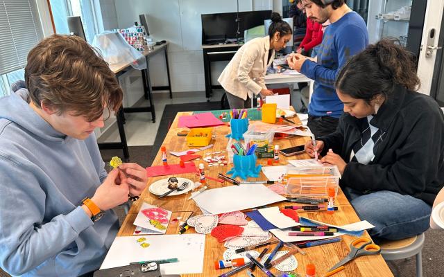 Students working in the Keller Center Makerspace at a table full of colorful paper and various art supplies.