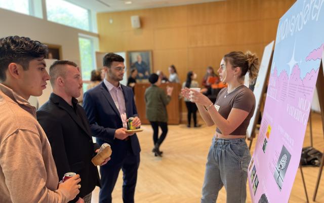 Students discussing their research in front of a poster 