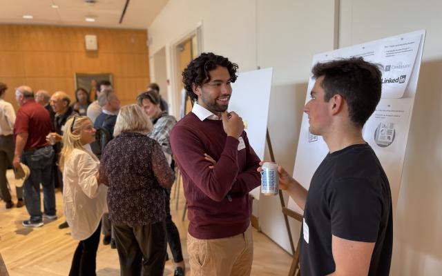 Students smiling and talking at a poster session