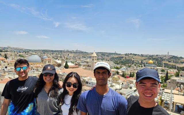 Smiling students standing on a balcony overlooking Tel Aviv