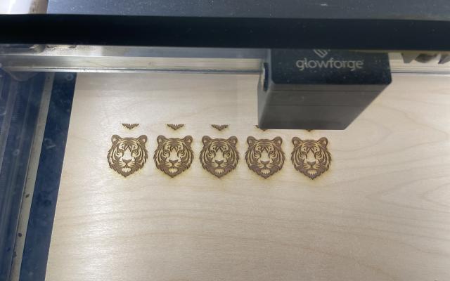 A laser cutting machine making a row of tiger heads