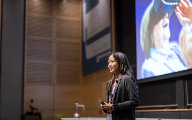 A woman gives a presentation in front of a large screen