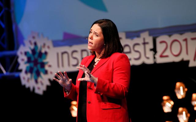 Woman with brown hair and red blazer presenting