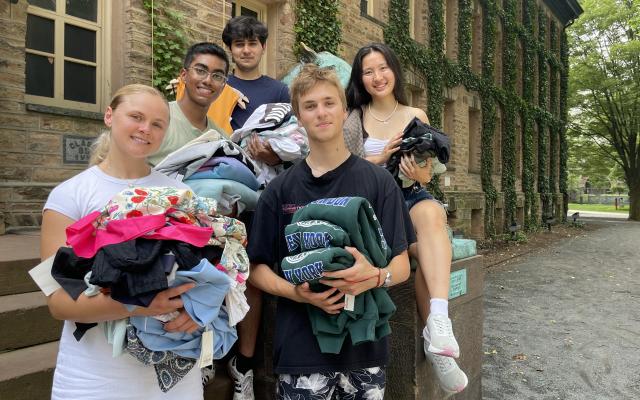 Members of the InstantReplay team standing outside of Nassau Hall holding piles of clothing