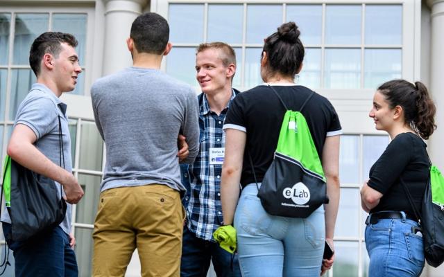 Five students standing in a circle and talking 