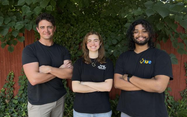 Lovestruck Games team members smiling in front of wooden fence and trees
