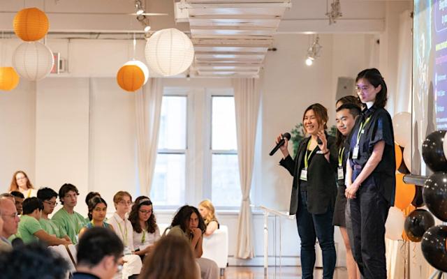 Students presenting on a stage with lanterns hanging from ceiling
