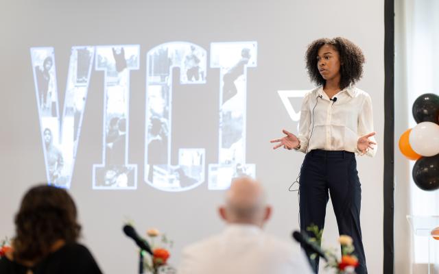 A young woemn pitching her start up with a display behind her that reads VICI