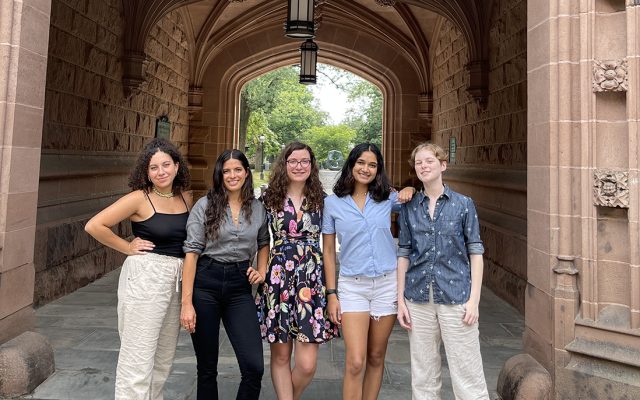 Team of five students standing under a gothic archway