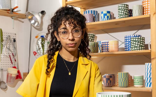 Sarah Hussaini standing at a table surrounded by her pottery. 