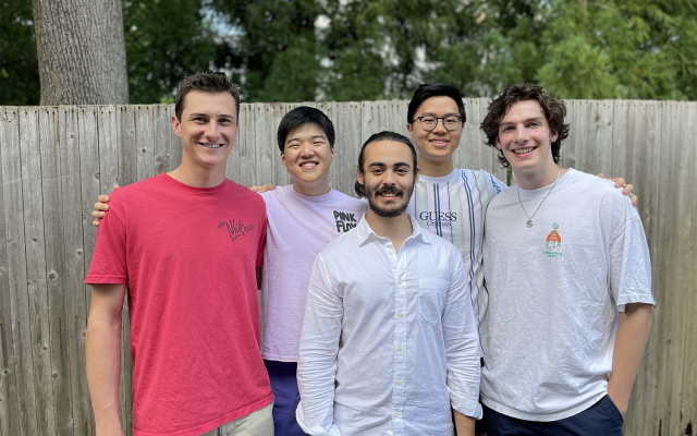 Five student team members smiling in a group outside