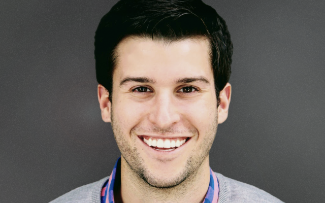 Man smiling with black hair wearing gray sweater