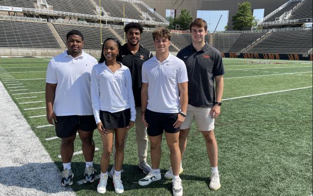Five students standing on college football field
