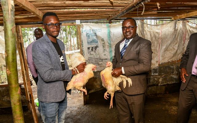 Two men holding live chickens