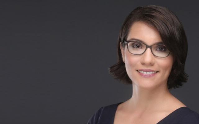 photo of a woman with dark hair wearing glasses and a black shirt, with a black background