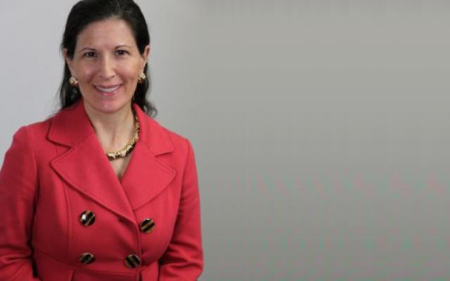 photo of a woman with dark hair wearing a red jacket, on a grey background