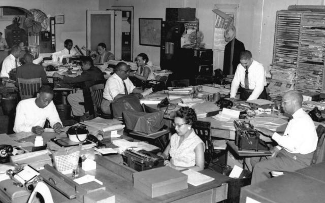 A black and white photo from the 60's showing an all Black news room