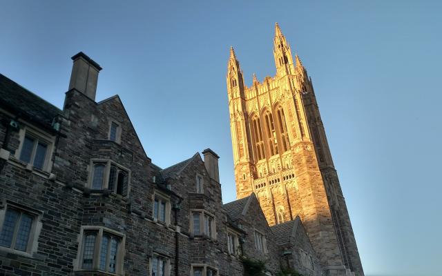 Princeton graduate school tower bathed in golden sunlight against a clear blue sky