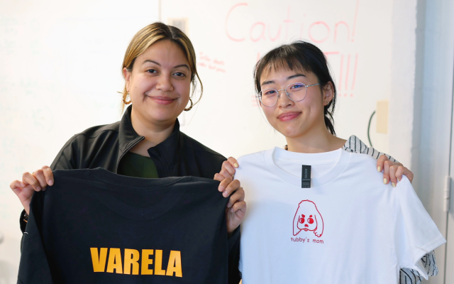 Two smiling women holding up t-shirts