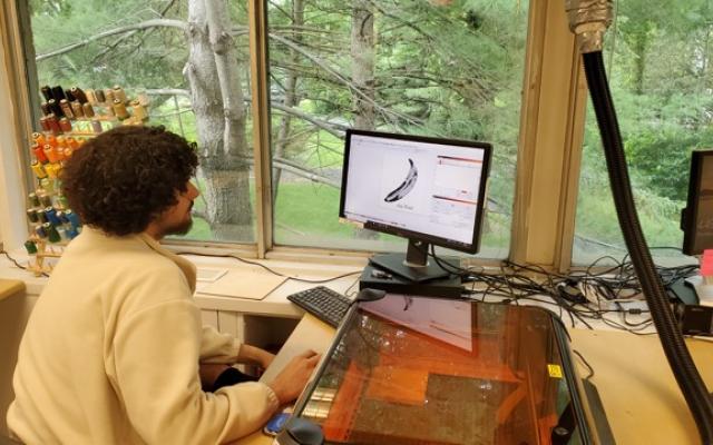Student sitting at computer to program a laser cutter