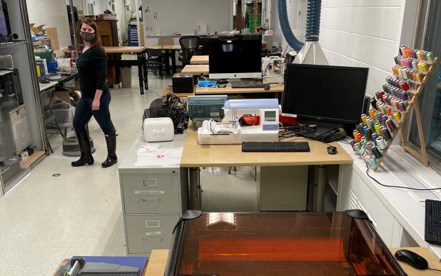 Carrie Collins standing in the makerspace amongst the tools and machinery