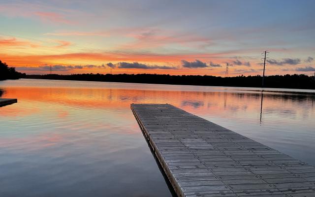 sunset reflected on a lake with along pier extending into the water.