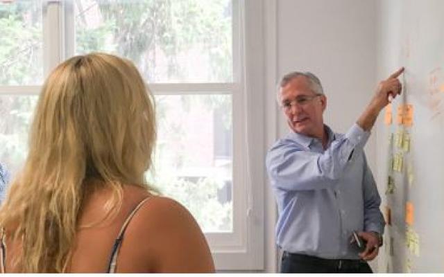 Teacher pointing at notes on wall while students watch