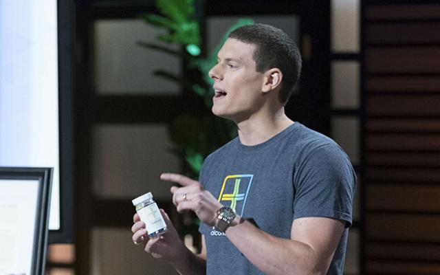 Brooks Powell holding a bottle as he presents on the television show Shark Tank