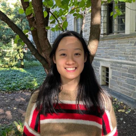 Annie Liu smiling in front of tree and stone building
