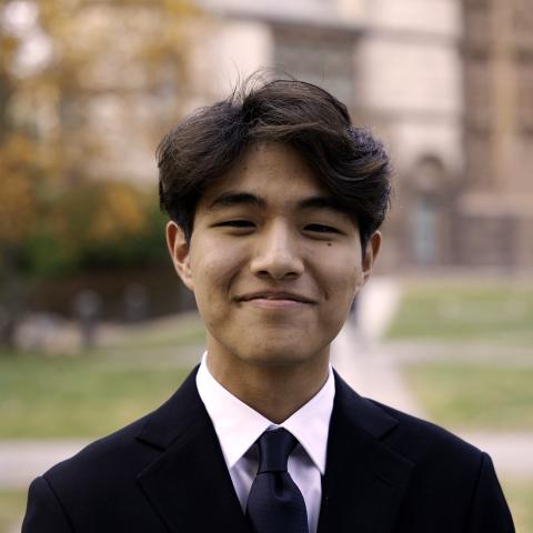 Student in a suit smiling outside