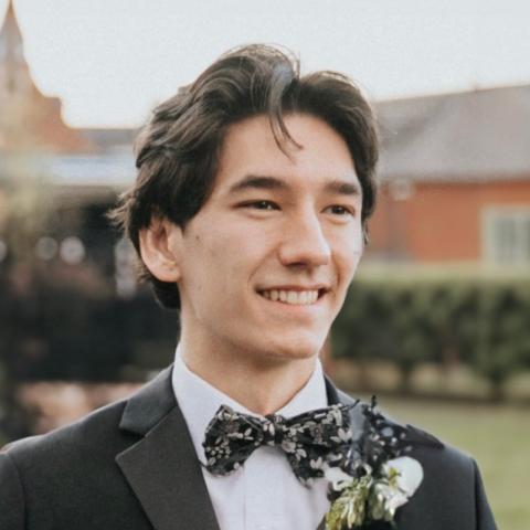 Student in a tuxedo smiling outside