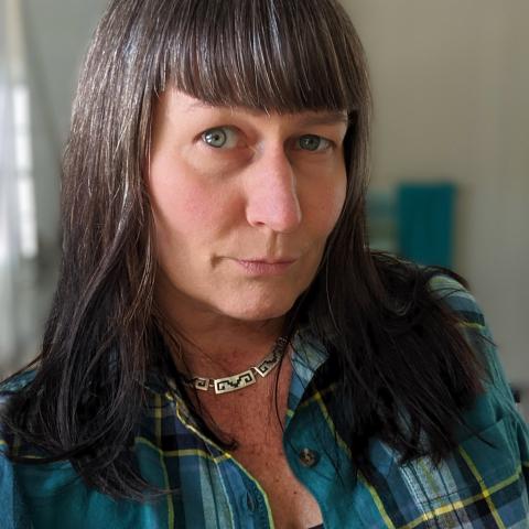 woman wearing a blue-green plaid shirt and long hair with bangs